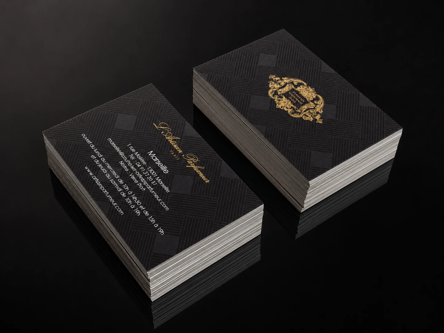 Luxury black business cards with ornate gold-foil monogram, stacked on dark surface, by City Images London