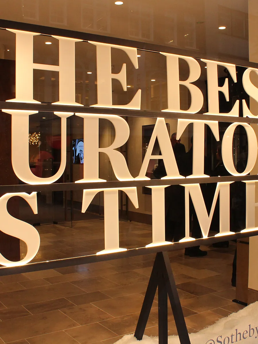 Backlit cut letterforms across the Sotheby's gallery window display in London