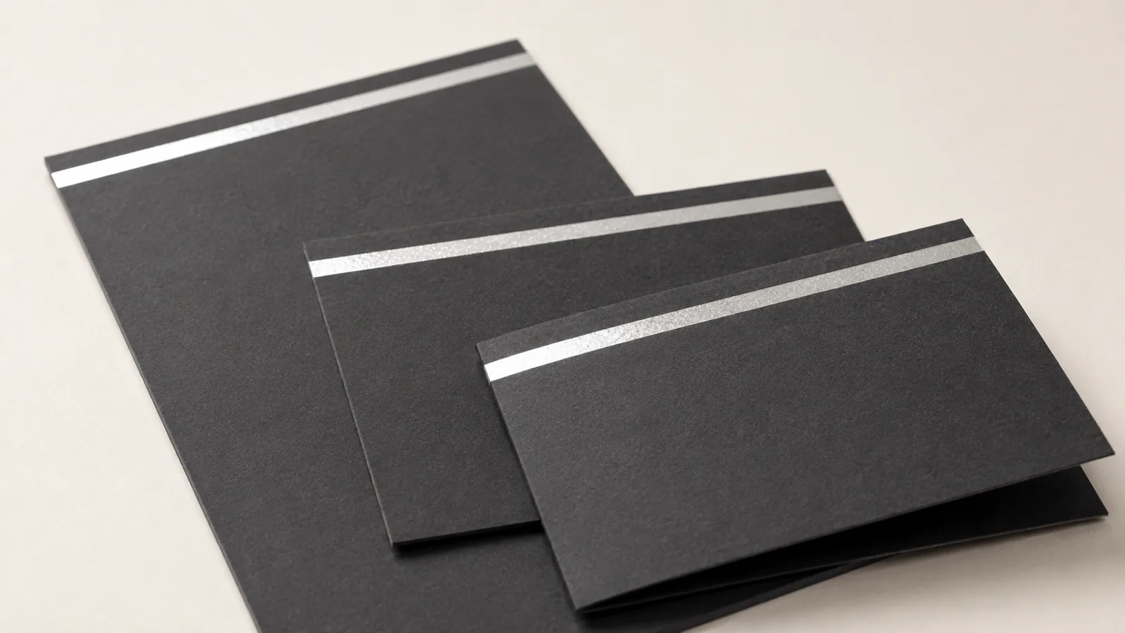 Invitation, reply card and folded card from one event set on charcoal board with silver foil