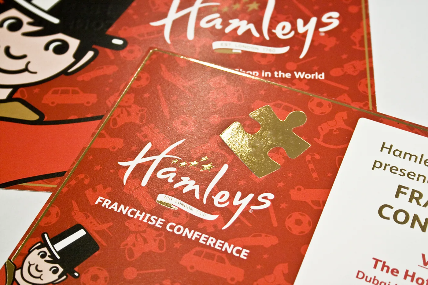 Hamleys franchise conference invitation in red with gold foil detail and border
