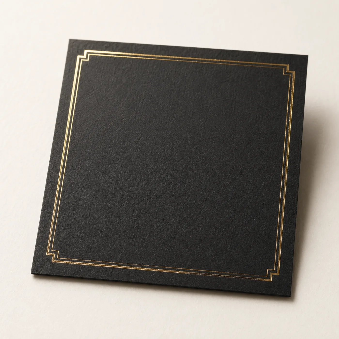 Black invitation card with a stepped gold foil border, showing how foil sits on dyed-through black board